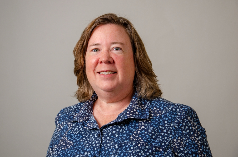 Portrait of Maria Bernier wearing a blue collared shirt with a flower print.